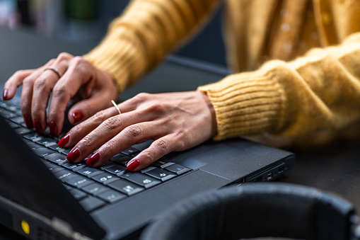 Close-up of womans hands using laptop in office.