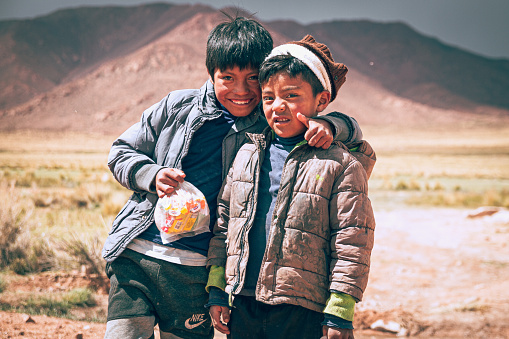 Salta, Argentina, 2022. Children from a community native to the Argentine Andes, with the mountains in the background, happy to receive donations from volunteers.