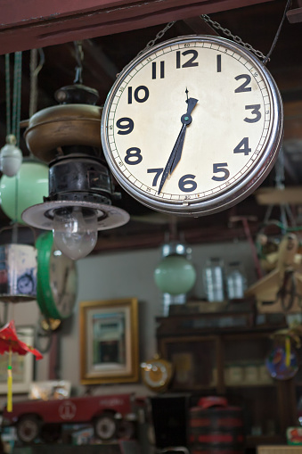 Vintage clock. Various vintage objects for sale at a indoor flea market. View of a display full of interesting old things for sale. Many groups of vintage assorted second-hand objects.