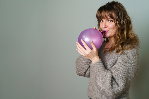 Young Woman Blowing a Purple Balloon