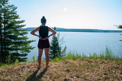 A woman stands with her arms on her hips by the Ottawa River during the summer