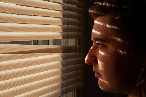 istock A woman looks through window blinds 1478122437