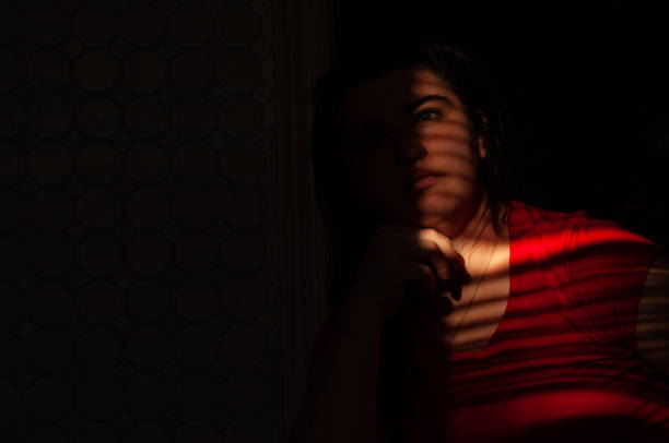 istock Venetian blinds create lines on a woman's face from the sunlight 1478122519
