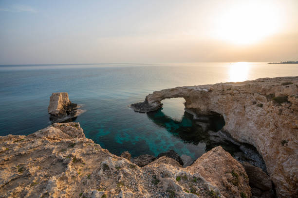 Beautiful sunset on natural rock arch near Ayia Napa in Cyprus. Bridge of lovers, Mediterranean Sea Beautiful sunset on natural rock arch near Agia Napa in Cyprus. Bridge of lovers, Mediterranean Sea ayia kyriaki chrysopolitissa stock pictures, royalty-free photos & images