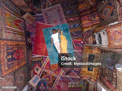 istock Drone view of couple lying on carpet and surrounded by carpets 1478126169