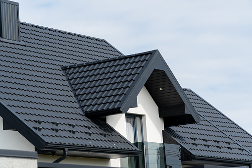 The roof of a modern new house. Tiled covering of building. Modern European house.