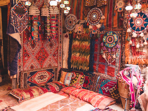 Amazing traditional handmade turkish carpets in the Bazaar market. Mosaic of colored fabrics. Lit in the evening, creating a cozy atmosphere