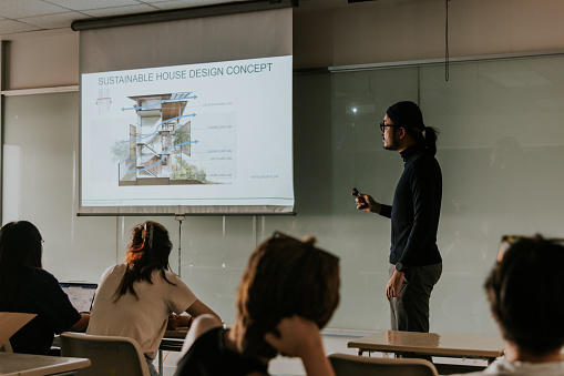 Asian hipster man who was a architect professor is teaching and sharing ideas and example about sustainable and eco concept for home and building  to his students in class, ventilation flow diagram in section detail.