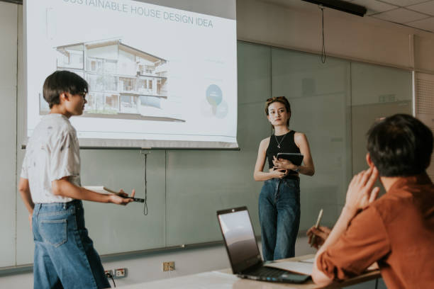 Teamwork presentation project, Sharing ideas and concepts sustainable house design to master's degree classmate. Coworker hipster architect students standing in front of the class and presenting their work project about ventilation flow and ideas function of sustainable house design to their classmate and discussing together. interior designing course stock pictures, royalty-free photos & images