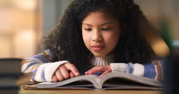 Photo of Kid reading book for learning, education and language development, literature or story knowledge. Biracial girl or child with library books or textbook for creative mind, storytelling and studying