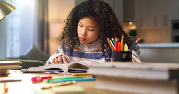 istock Girl, education or student reading a story in a school notebook for homework or knowledge. Focus, fun or young female kid enjoys learning, studying or working in house alone for child development 1478130282