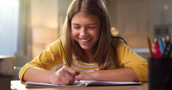 Learning, education and child writing and happy with notebook and studying for school exam or test. Girl kid student with pencil for notes in a book for development, knowledge and study at home desk