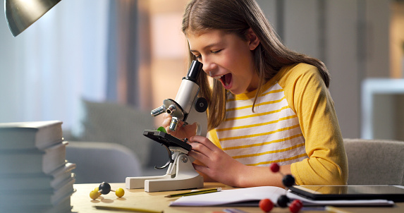 Breakthrough, research and science student shocked at discovery while looking through a microscope at night. Surprised, amazed and young person learning or working on a project feeling happy