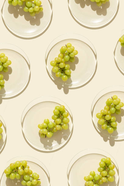 istock Food pattern from bunch white grapes on glass plate with shadows at sunlight, minimal style summer fruit on beige colored fon, green berries of grape, top view, trend flat lay, food 1478134020