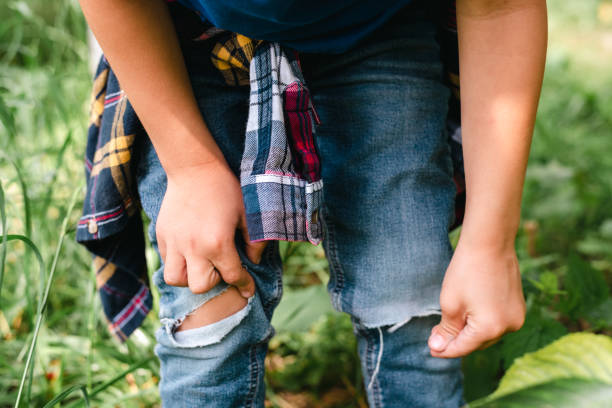 istock Little boy examines his jeans, torn at the knees. 1478134531