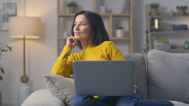 istock Laptop, remote work and woman thinking by planning on a lounge sofa at home. Freelance writing, creative ideas and relax person busy with digital web research for an email on a living room couch 1478140928