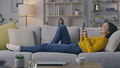 Phone, sofa and woman relax in a living room, browsing or checking social media in her home. Smartphone, chilling and lady on a couch with app, website or chatting online while resting indoors