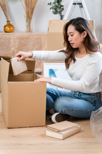 istock Young woman unpacking boxes in new apartment 1478144304