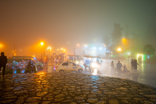 Sapa city, Lao Cai province, Vietnam - 12 Mar 2023: Night life in Sapa, Vietnam, tourists and locals walking at the square in the center of Sapa at the evening, misty night and wet street.