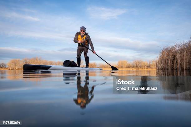 Senior Paddler On His Paddleboard On Lake In Winter Or Early Spring In Colorado Stock Photo - Download Image Now