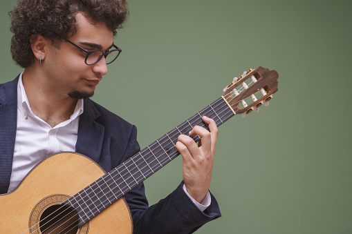 Portrait of a young musician playing classic guitar, Studio shot