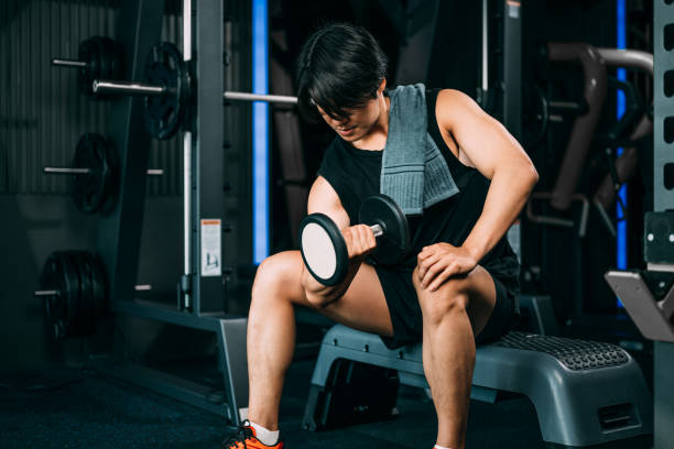 istock Young man bodybuilder lifting heavy weights dumbbell workout at gym 1478155694