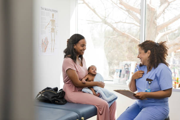 Young adult mother proudly smiles while listening to the nurse admire her son