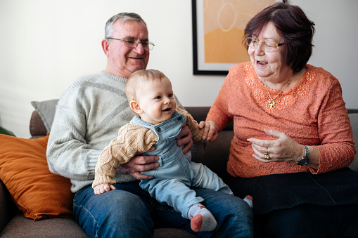 Grandparents are sharing a sweet moment with their charming grandson at home.