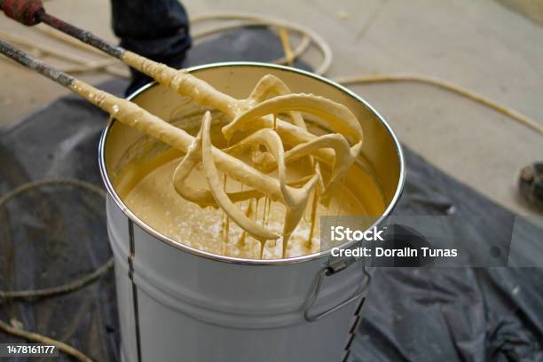 The Worker Is Carefully Mixing Epoxy Composites In A Metal Bucket To Create Highquality Polyurethane Resin This Process Requires Precision And Attention To Detail To Ensure The Resin Is Mixed Correctly For Optimal Performance Stock Photo - Download Image Now