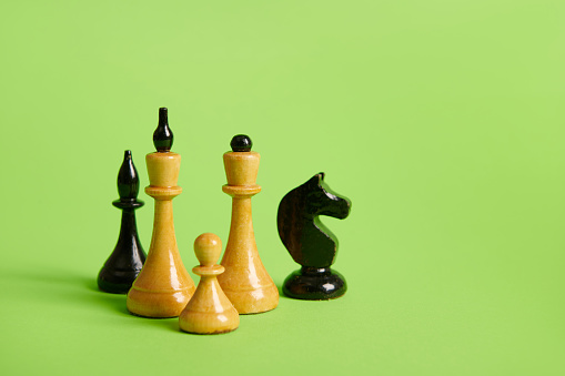 Black and white chess pieces on green isolated background with copy advertising space. King Queen Knight, pawn and horse. Leisure and board games concept. Development of business strategy concept