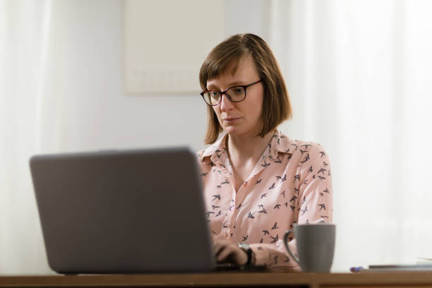 istock Woman in pajamas working on laptop computer from home office 1478162742