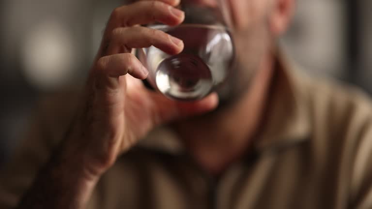 Close up smiling man taking pill, holding water glass