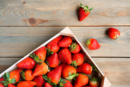 Fresh strawberries in wooden box on wooden table. Harvest concept. Close-up