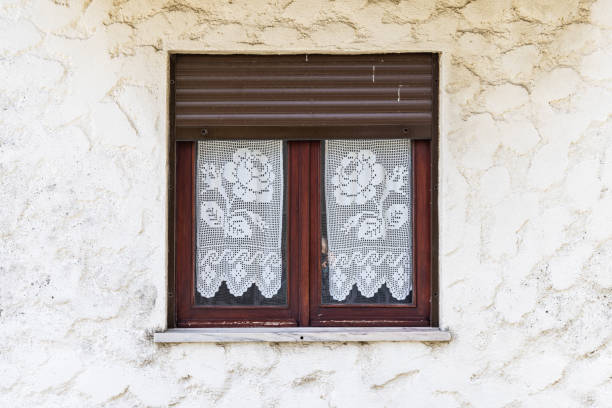 istock Lace curtains in a window on a stucco wall. 1478176271