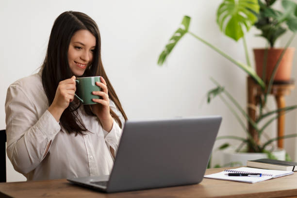 istock Young woman holding a cup and having a video call 1478178631