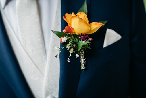 A smartly dressed person at wedding wearing a suit and a coordinating bow tie with flowers in a pocket