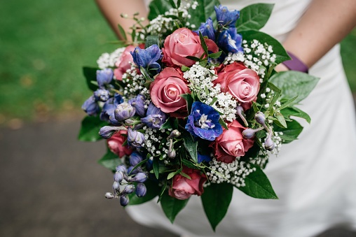 A bouquet of flowers in the hand of a bride in a white dress