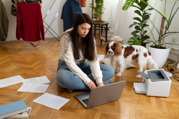istock Young woman using laptop computer on the floor at home with dog 1478179052