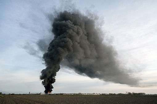 Chemical solvent plant burns down with a black column of toxic smoke.