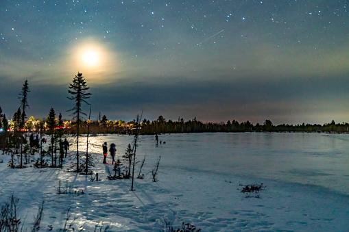 People are waiting for the appearance of the aurora standing on the ice of Highland Lake inTorrance Barrens Dark-Sky Preserve, Ontario, Canada.