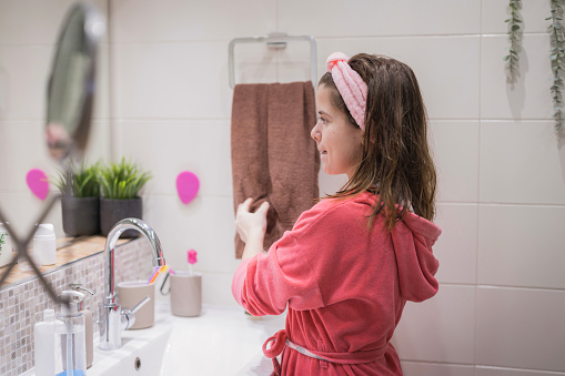 Girl looking in the mirror when drying hands in a bathrobe