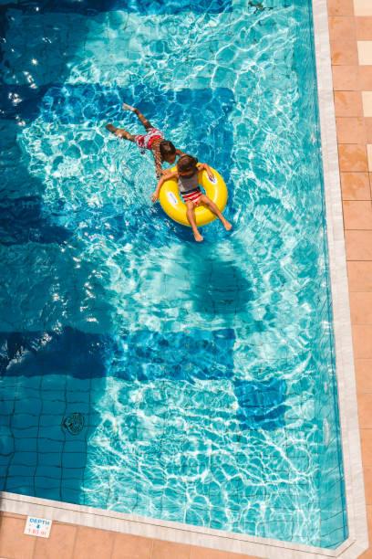 Children playing with inflatable ring in swimming pool Above shot of Children having fun playing on inflatable ring into the swimming pool young hot stock pictures, royalty-free photos & images