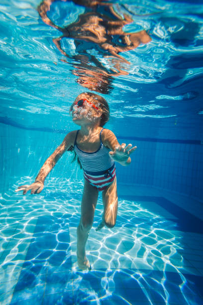 Little girl having fun diving underwater into the swimming pool