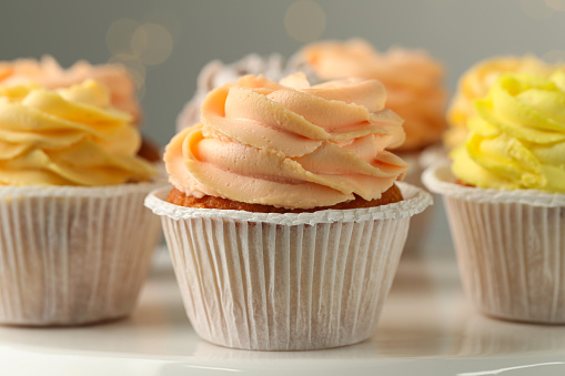 Tasty cupcakes on white table against blurred lights, closeup