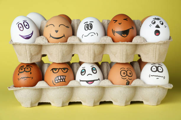 istock Eggs with different drawn faces in cardboard packages on pale yellow background 1478192050