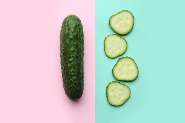 istock Whole and cut cucumbers on color background, flat lay 1478192075