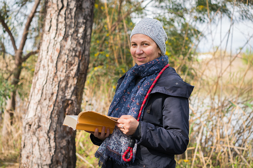 Pretty women with reading interesting story book. Attractive mature woman holding textbook and looking at camera.