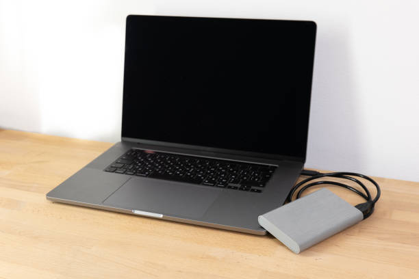istock External hard drive connected to laptop computer. Portable hard drive connected to a laptop computer on a wooden table. Data transfer or backup between a laptop and a hard disk. 1478193287