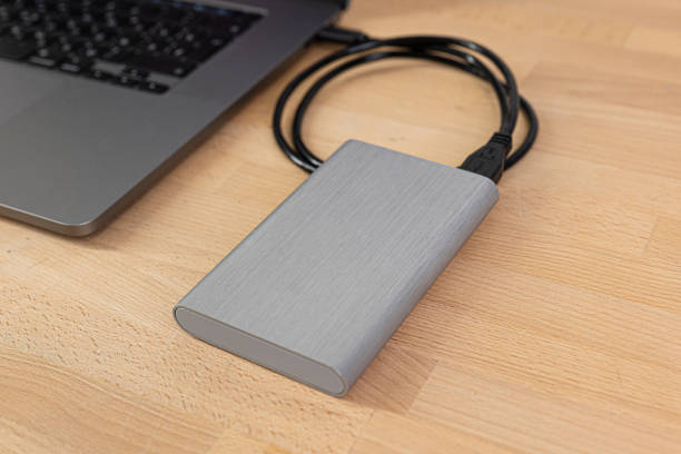 istock External hard drive connected to laptop computer. Portable hard drive connected to a laptop computer on a wooden table. Data transfer or backup between a laptop and a hard disk. 1478193297