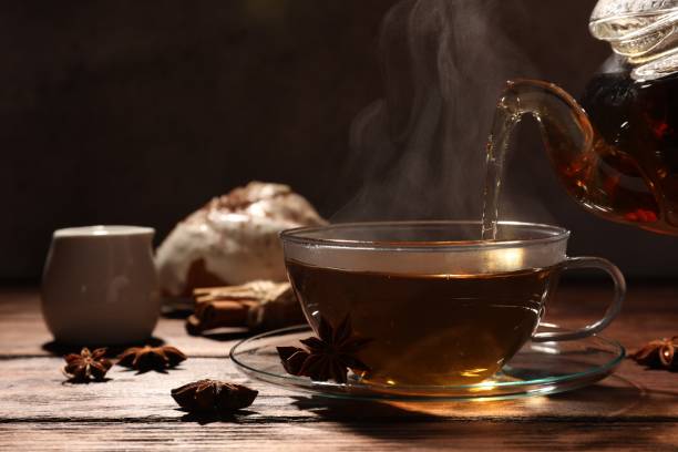 istock Pouring aromatic anise tea into glass cup on wooden table 1478195761